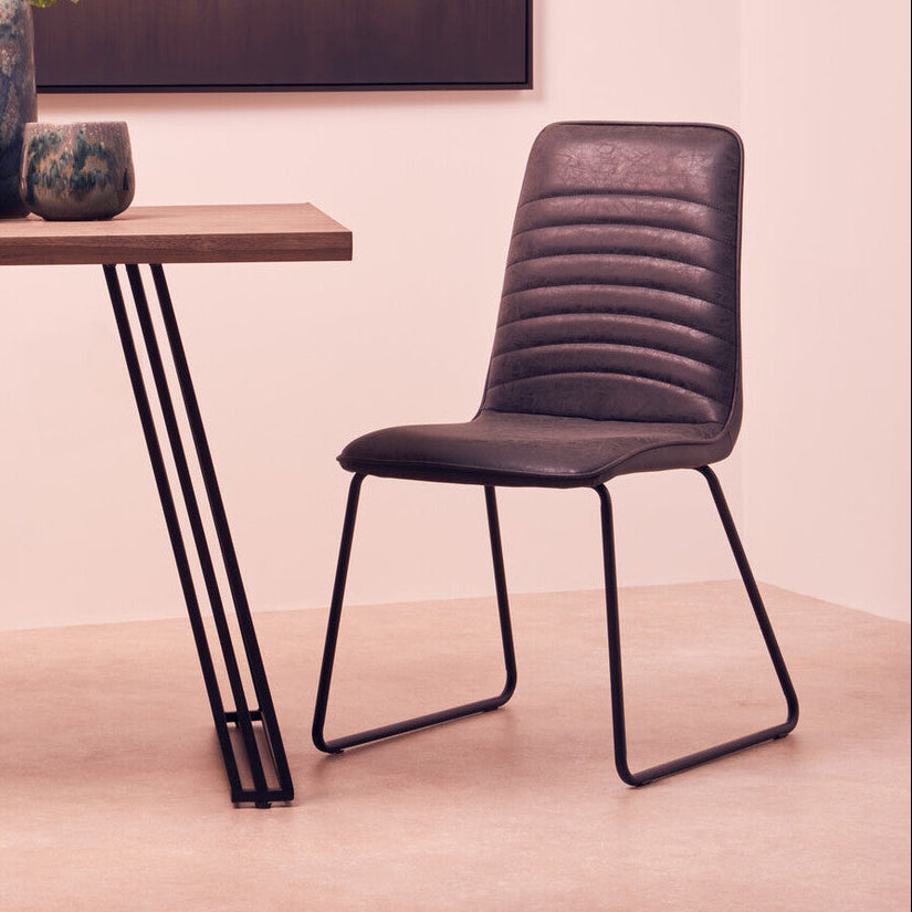 Modern chair next to a wooden table with decorative items in a room.