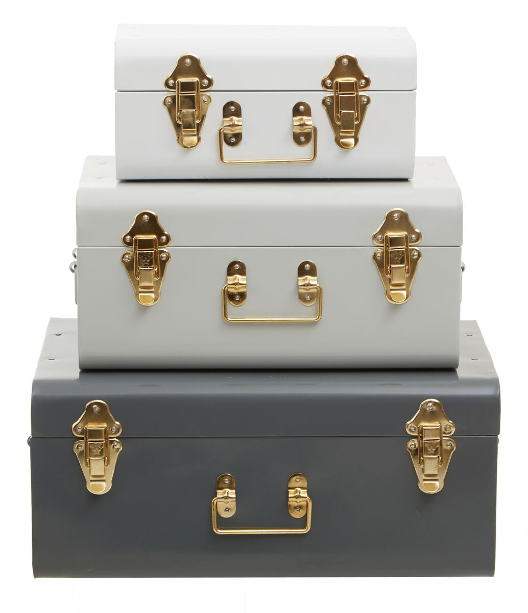 Set of three stacked trunks in white, gray, and light blue with gold latches on a white background.