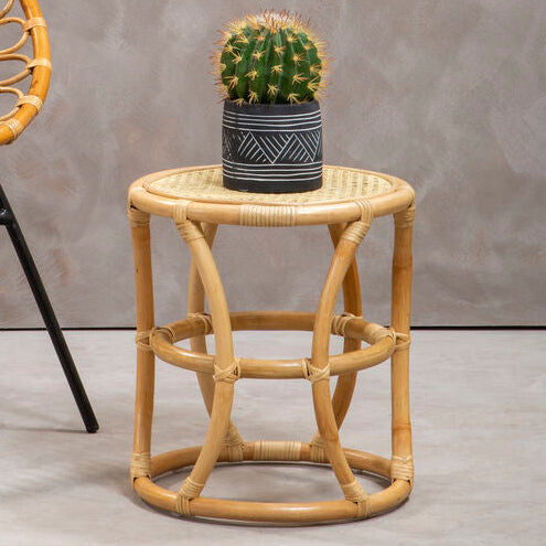 Rattan chair and side table with a cactus plant against a gray wall.