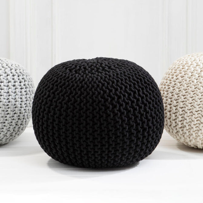 Three knitted poufs in black, white, and gray on a light background