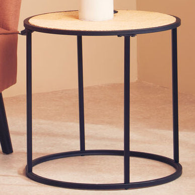 Orange chair and black side table against a beige wall with a framed leaf print.