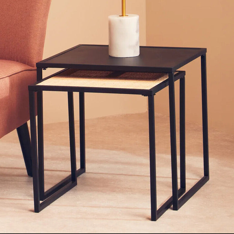 Nest of tables with a lamp and vase next to an orange armchair in a room.