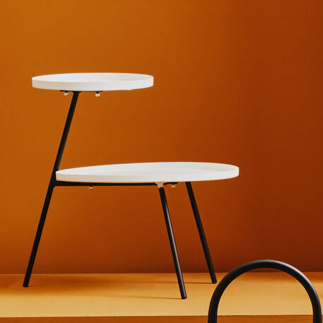 Modern side tables against a warm orange wall