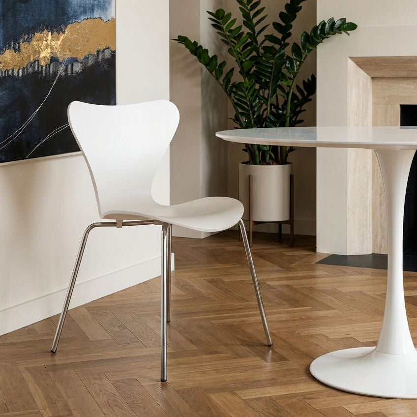 White chair with metal legs in a room with a white table and plant.