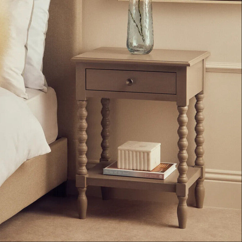 Neatly arranged bedroom with a bed, nightstand, and decorative elements.