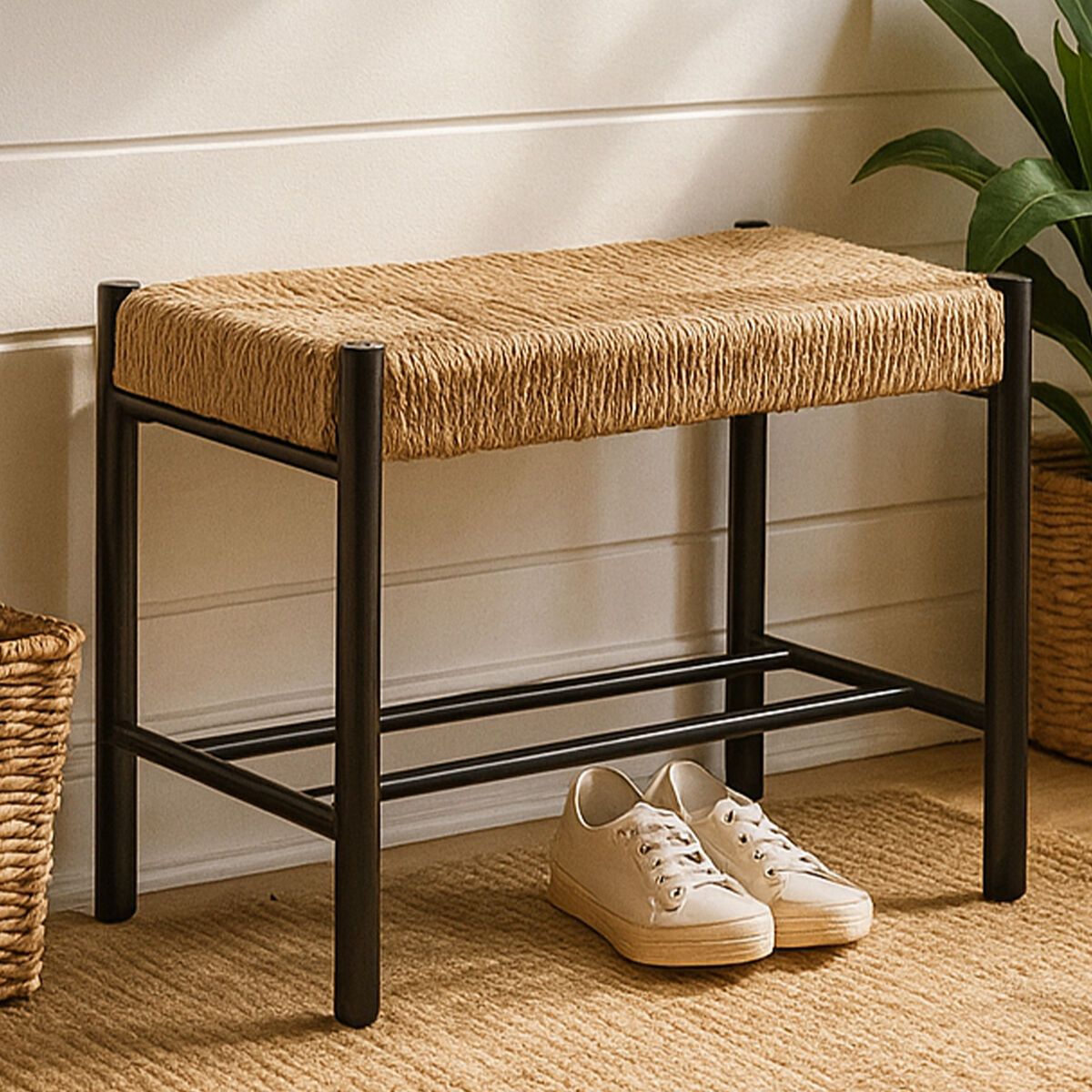 Woven stool with black frame and beige cushion on a wooden floor with white wall background