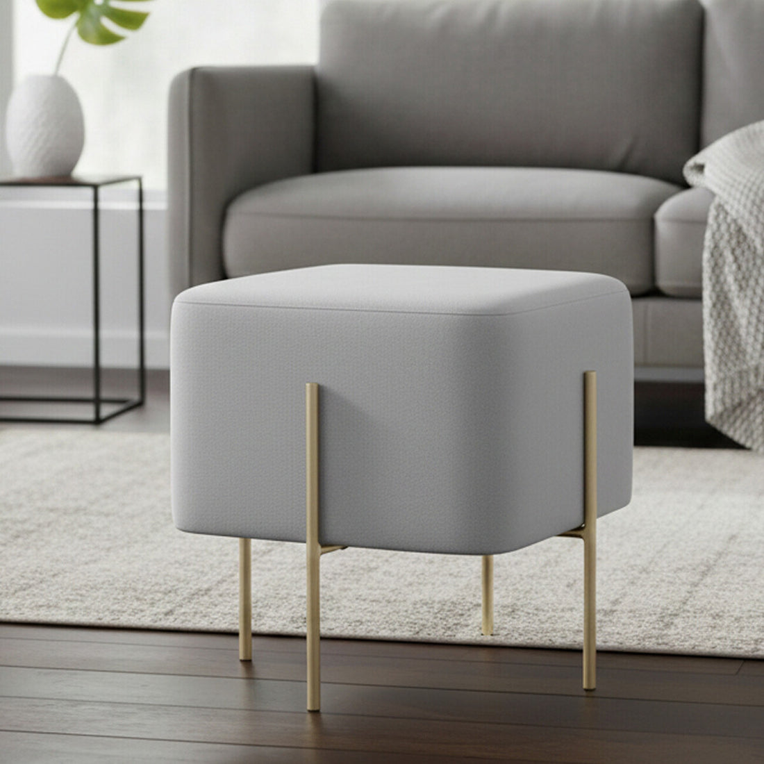 Gray ottoman with gold legs in a living room setting