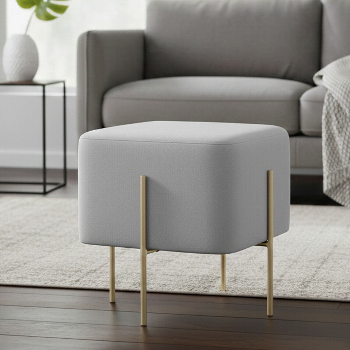 Gray ottoman with gold legs in a living room setting