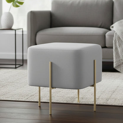 Gray ottoman with gold legs in a living room setting