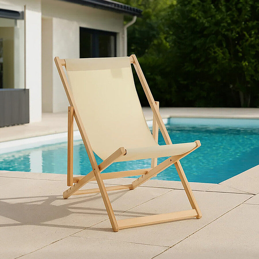Beige deck chair on a patio by a poolside with greenery in the background