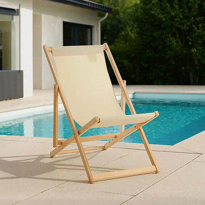 Beige deck chair on a patio by a poolside with greenery in the background