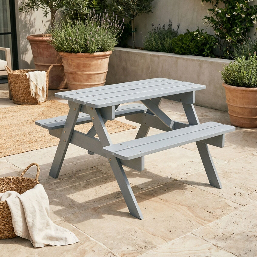 Gray outdoor picnic table with potted plants in a garden setting