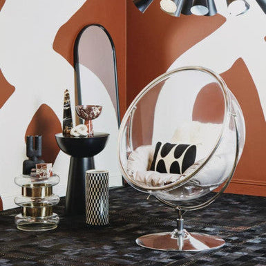 Modern interior design with a glass chair, decorative items, and abstract wall art.