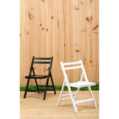 Two folding chairs, one black and one white, on a wooden deck with a wooden fence background.