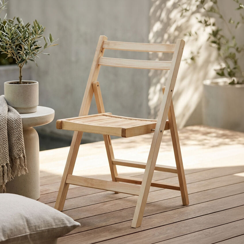 Wooden folding chair on a wooden deck with plants and a pillow in the background