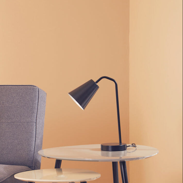 Gray sofa with two side tables and a black lamp against a beige wall.