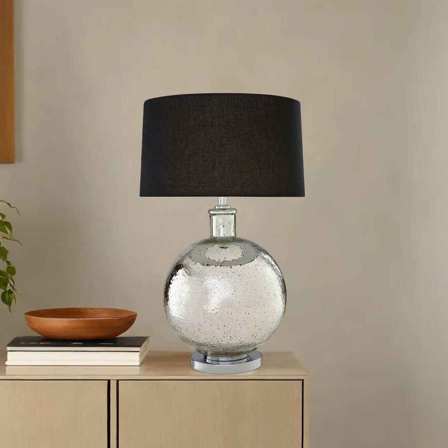 Decorative lamp with black shade on a cabinet against a beige wall