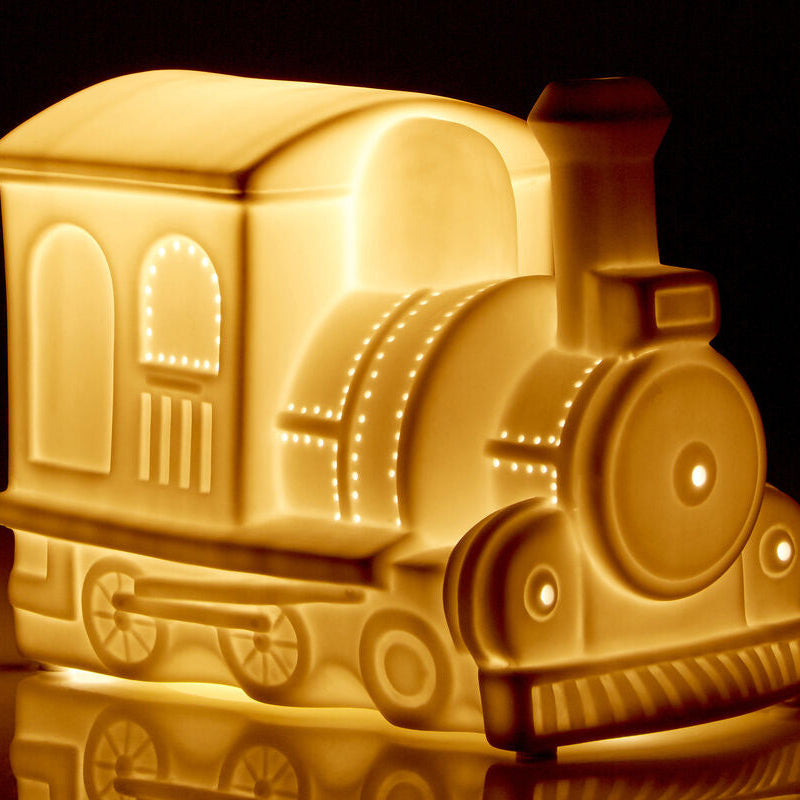 Train-shaped night light emitting a warm glow on a dark background