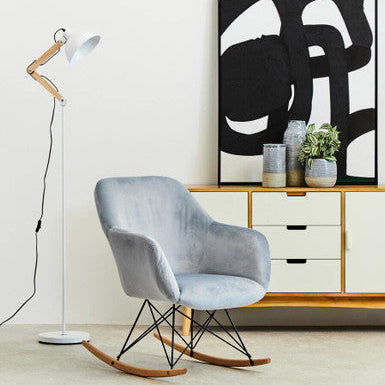 Modern interior with a gray rocking chair, floor lamp, and abstract art.