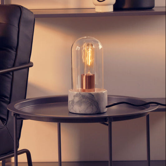 Modern brown leather armchair with a side table featuring a decorative lamp in a room setting.