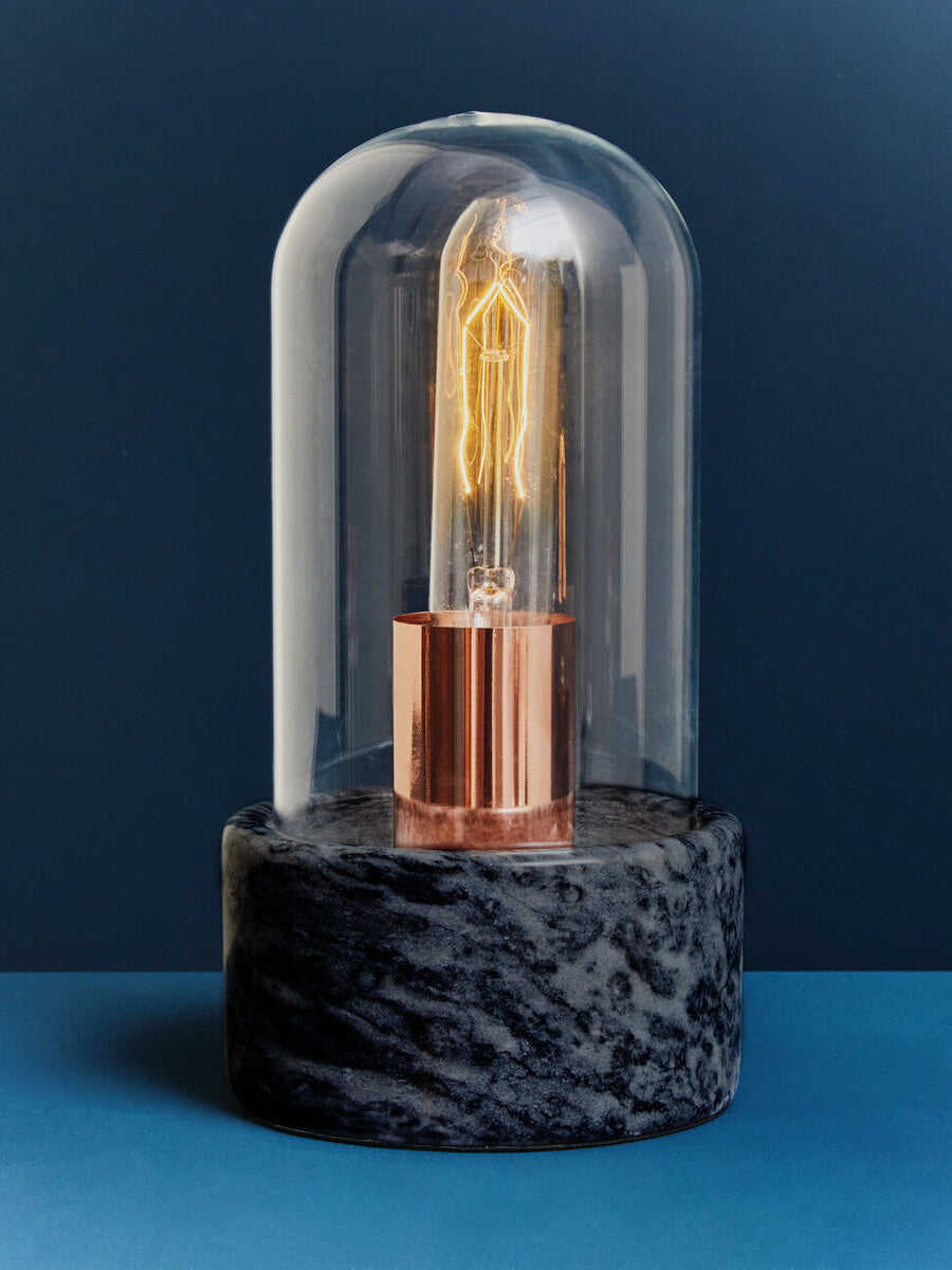 Decorative light bulb on a dark marble base against a blue background
