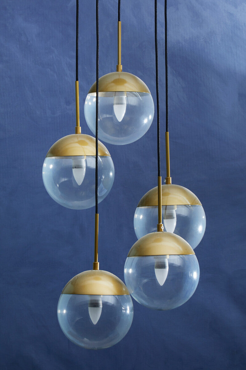 Set of four pendant lights with gold bases and clear glass shades against a blue background