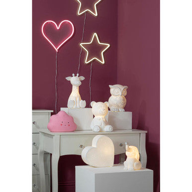 Decorative scene with neon lights, small animal figurines, and a pink lamp on a white surface against a purple wall.