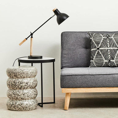 Modern living room with gray sofa, black lamp, and textured side table.