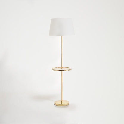 Floor lamp with a white shade and gold base on a light gray background