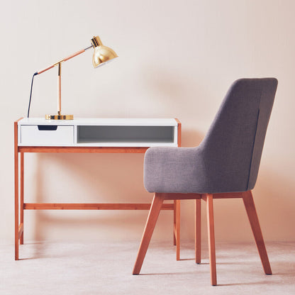 Modern desk with lamp and chair against a plain wall