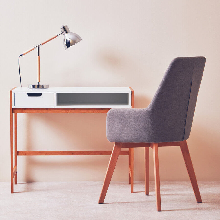 Minimalist desk with lamp and chair against a plain wall