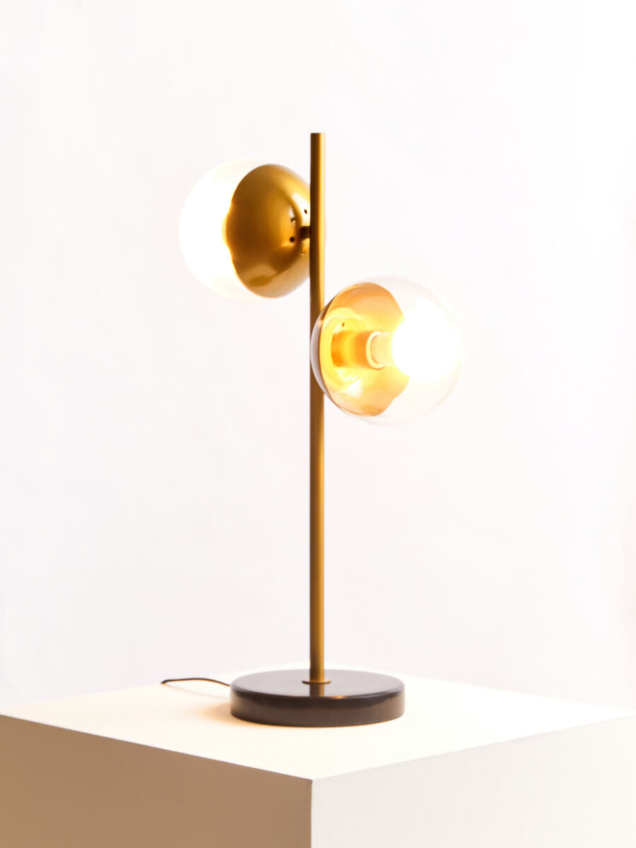 Modern table lamp with gold finish and black base on a white surface