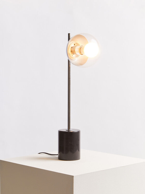 Modern table lamp with a black base and glass shade on a white surface.
