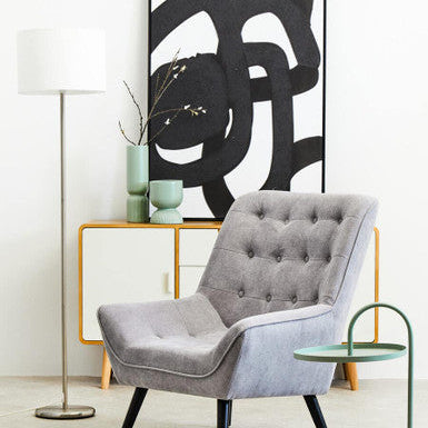 Gray armchair in a modern living room with abstract art and side table.