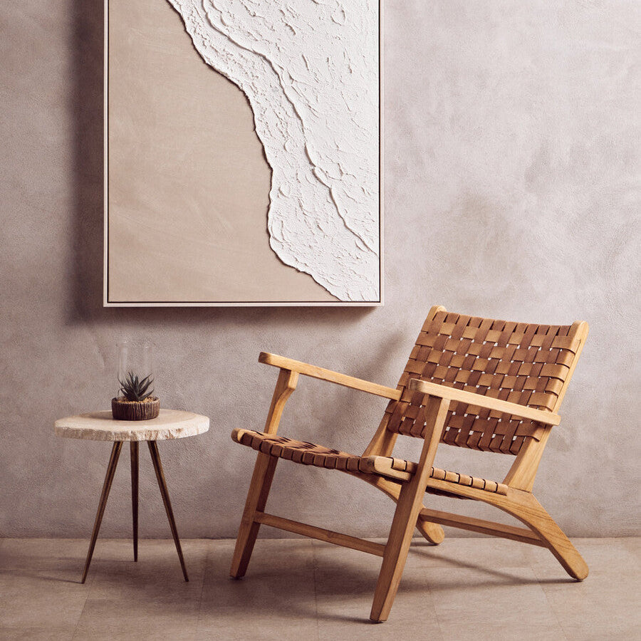 Wooden armchair and side table in a room with a large abstract painting on the wall.