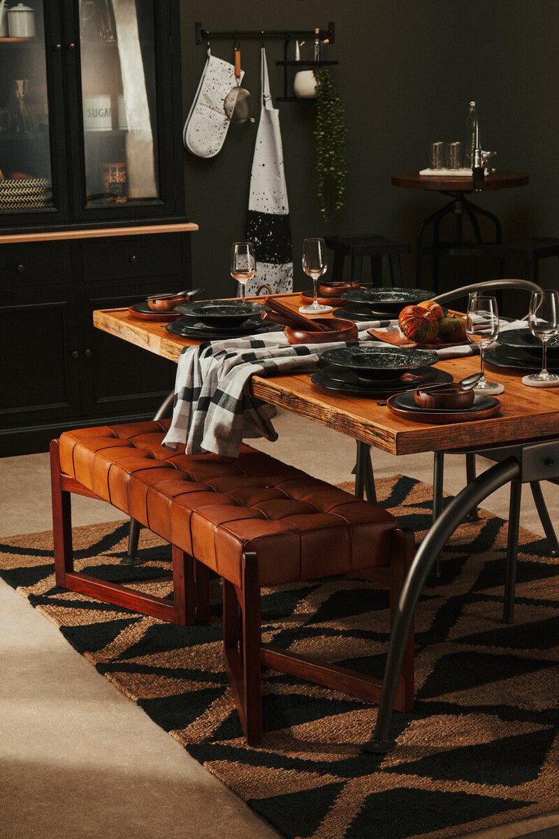 Dining room with wooden table, leather bench, and dark walls.
