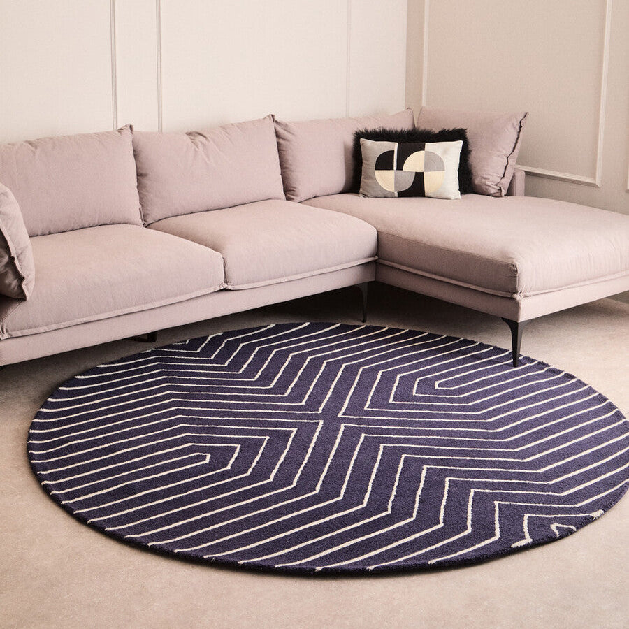 Round blue and white striped rug in front of a beige sectional sofa.
