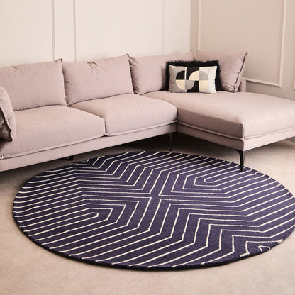 Round blue and white striped rug in front of a beige sectional sofa.