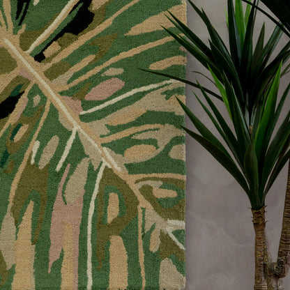 Decorative wall art with leaf pattern next to a potted plant on a neutral wall.