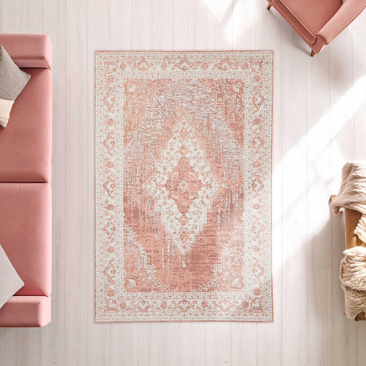 Patterned pink and beige rug on a light wooden floor with a pink sofa and decorative items.