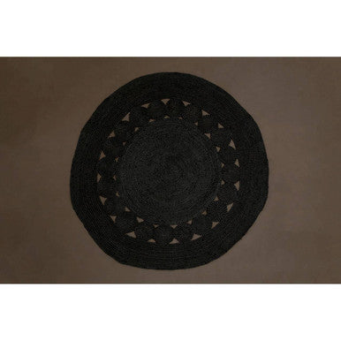 Black woven mat with cut-out patterns on a brown background