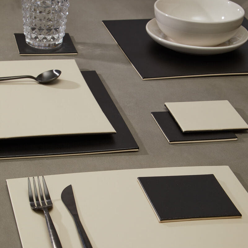 Dining table setting with placemats, cutlery, and glassware on a neutral background
