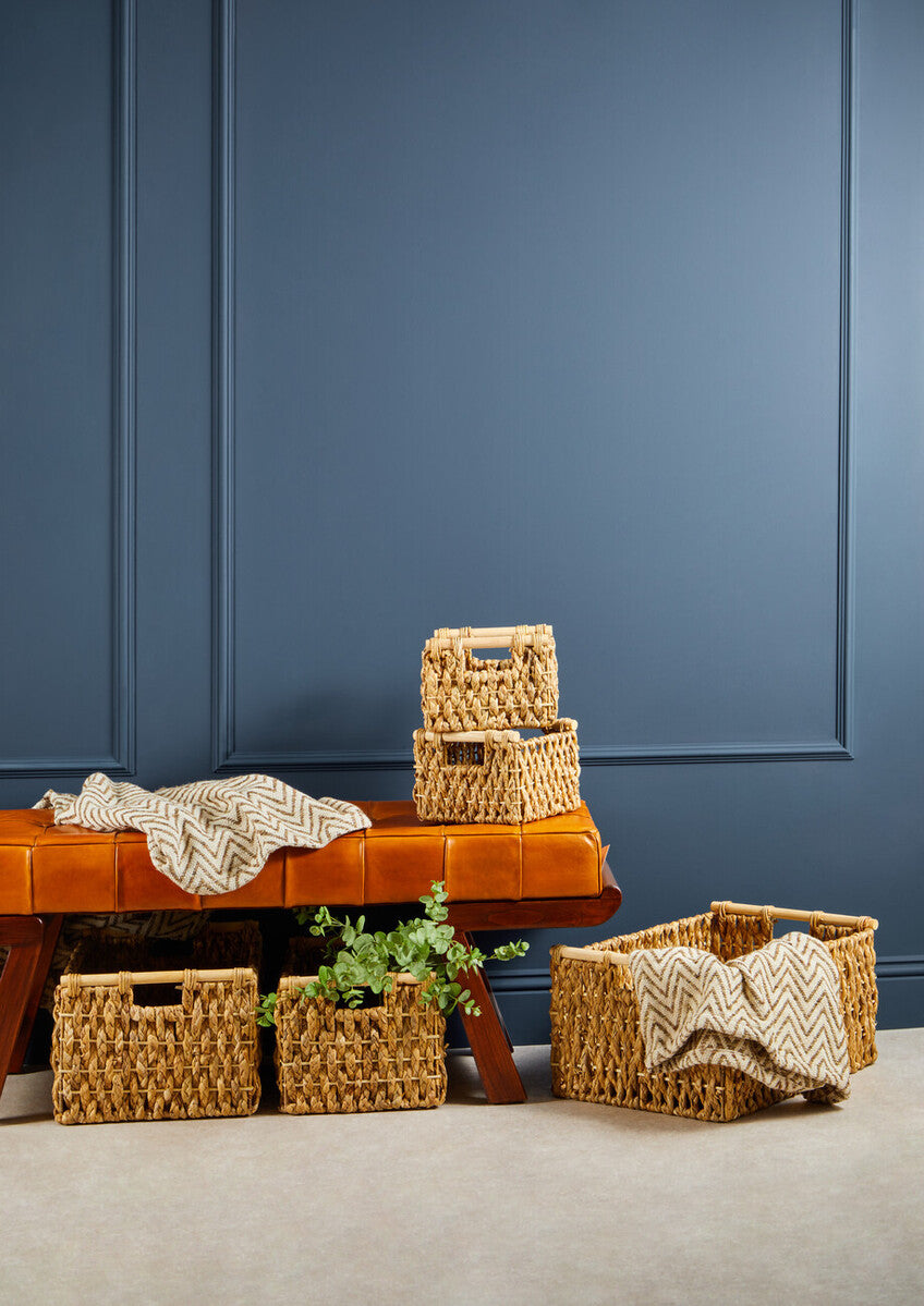 Woven baskets and a leather bench against a blue paneled wall.