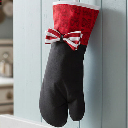 Black oven mitt with a red and white bow hanging on a hook in a kitchen.