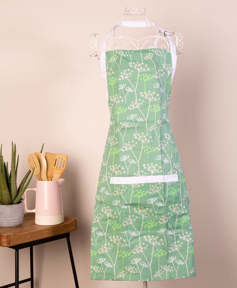 Green apron with floral pattern hanging on a white rod against a beige wall.