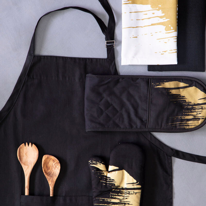 Black apron with gold accents, oven mitt, pot holder, and wooden spoons on a gray background