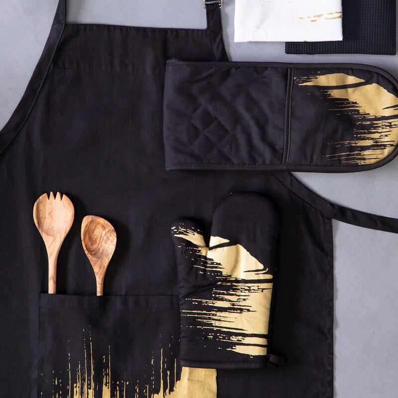 Black apron with gold accents, oven mitt, pot holder, and wooden spoons on a gray background