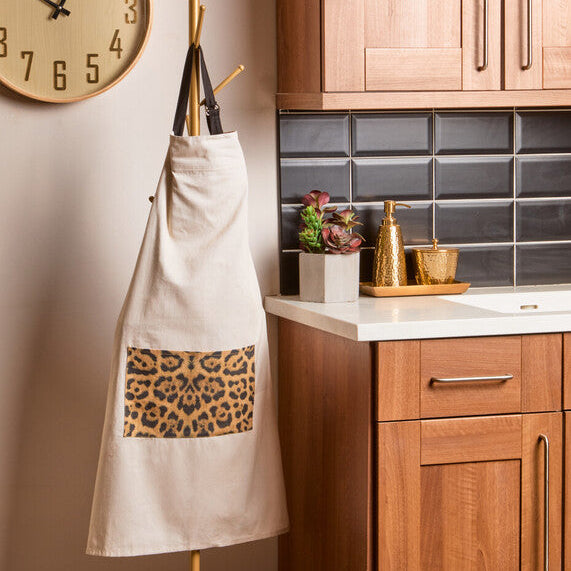 Kitchen with wooden cabinets, a clock on the wall, and an apron hanging on a stand.