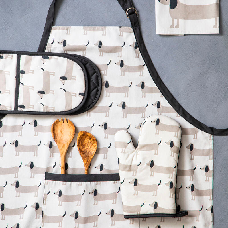 Set of kitchen towels with dog pattern, wooden spoons, and a black strap on a gray surface.