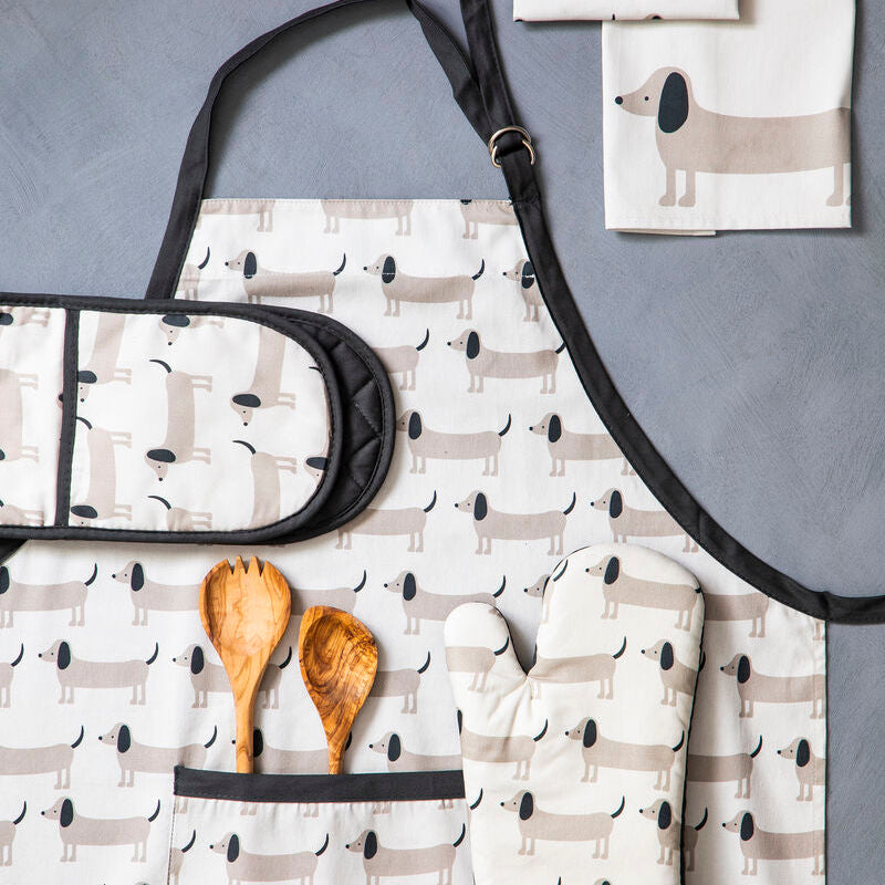 Set of kitchen towels with dog pattern, wooden spoons, and a black strap on a gray surface.